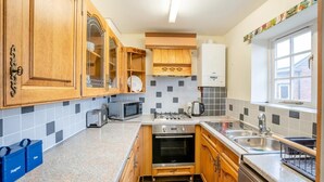 A kitchen with wooden cabinets, a microwave, a stove, and a sink. - 2 Bed in Hunston (oc-g36324) (Hunston)