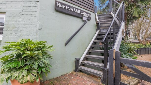 En trappa som leder upp till en byggnad med skylten ”Hunston Mill Cottages”.