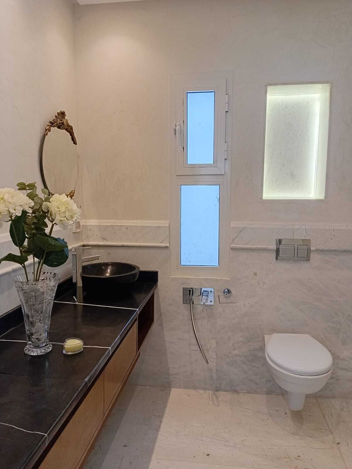 Ein Badezimmer mit Toilette, Waschbecken mit Spiegel und Fenster mit Milchglas.