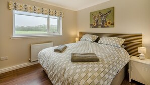 A bedroom with a large bed, a window with a view, a radiator, and a painting on the wall. - 2 Bed in Ochiltree (oc-w37517) (Ochiltree)