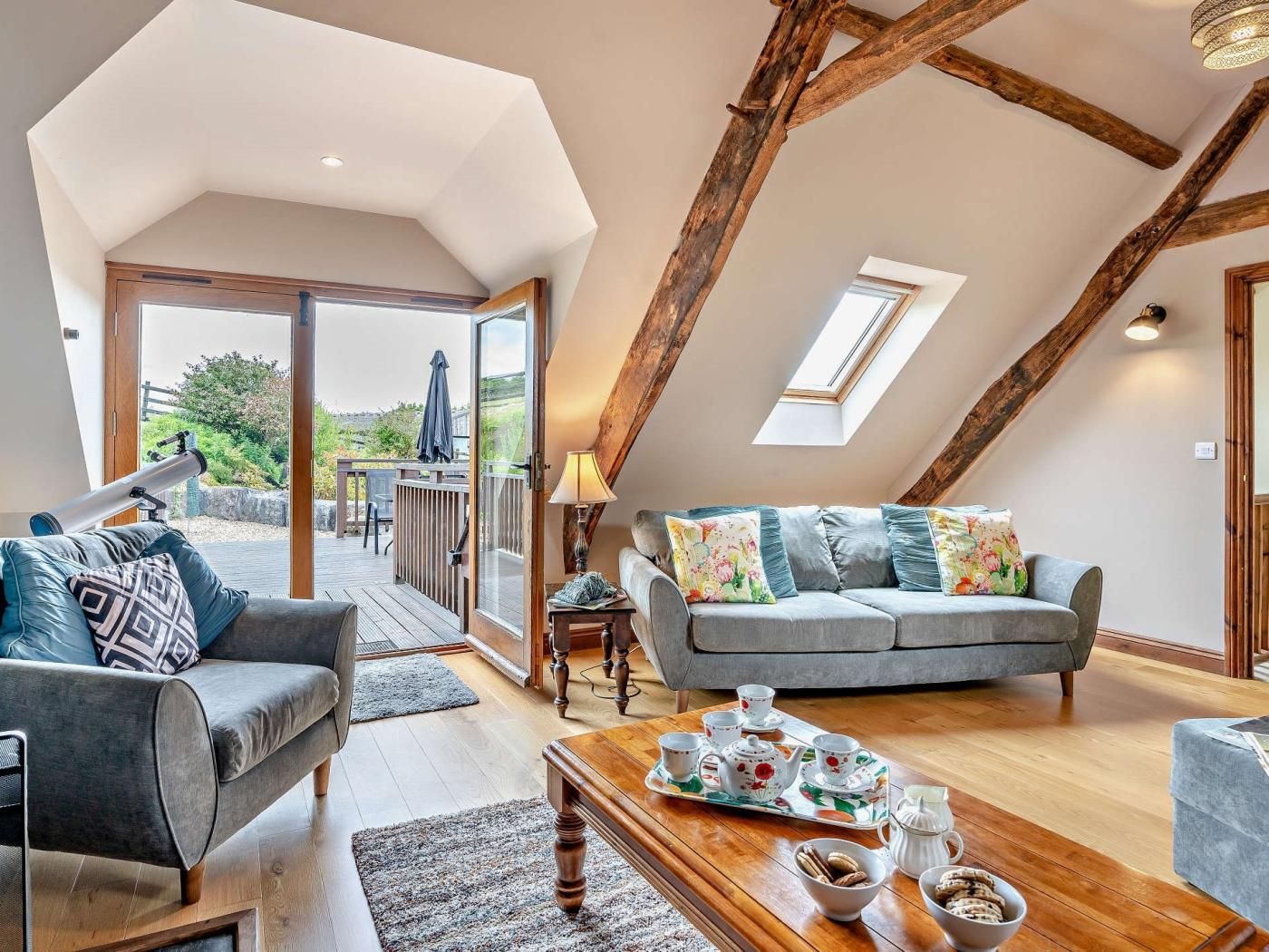 Una habitación tipo loft con techo de madera, un conjunto de sofás, una mesa de centro con juego de té y vistas a una terraza exterior a través de una puerta de cristal.