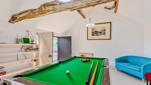 Een pooltafel met een groen vilt oppervlak, een blauwe bank en een ingelijste foto aan de muur.