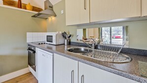 Een moderne keuken met witte kastjes, een roestvrijstalen spoelbak, een magnetron en een afdruiprek.