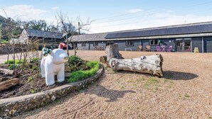 Un edificio con un grande tronco, una scultura bianca e un'area ghiaiosa.