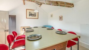 Ein Essbereich mit einem langen Tisch, roten Stühlen und einem Holzbalken an der Decke.