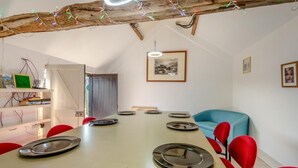 Ein Essbereich mit einem langen Tisch, roten Stühlen und einem blauen Sofa.