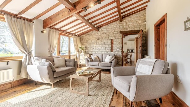 A cozy living room with a stone wall, wooden beams, and a view of the kitchen. - 2 Bed in Great Edstone (oc-t36332) (Great Edstone)