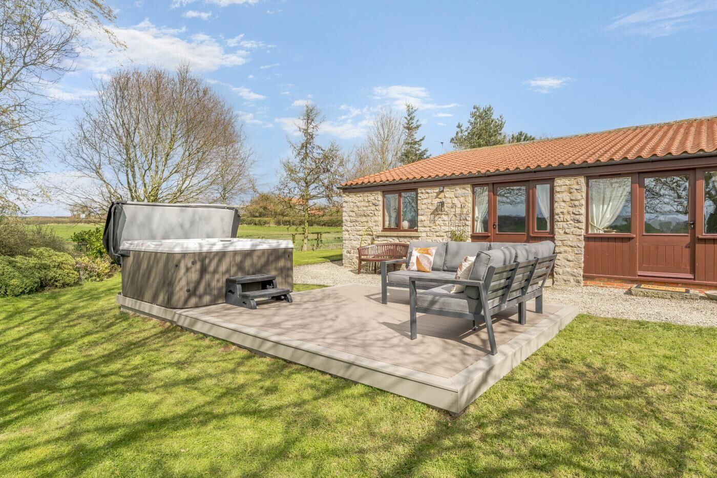A patio with outdoor furniture, a barbecue grill, and a stone building with a tiled roof.