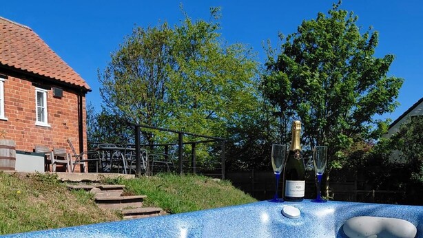 A hot tub with a control panel, two glasses, and a bottle of champagne in a backyard setting. - 2 Bed in Wrangle (oc-t37494) (Old Leake)