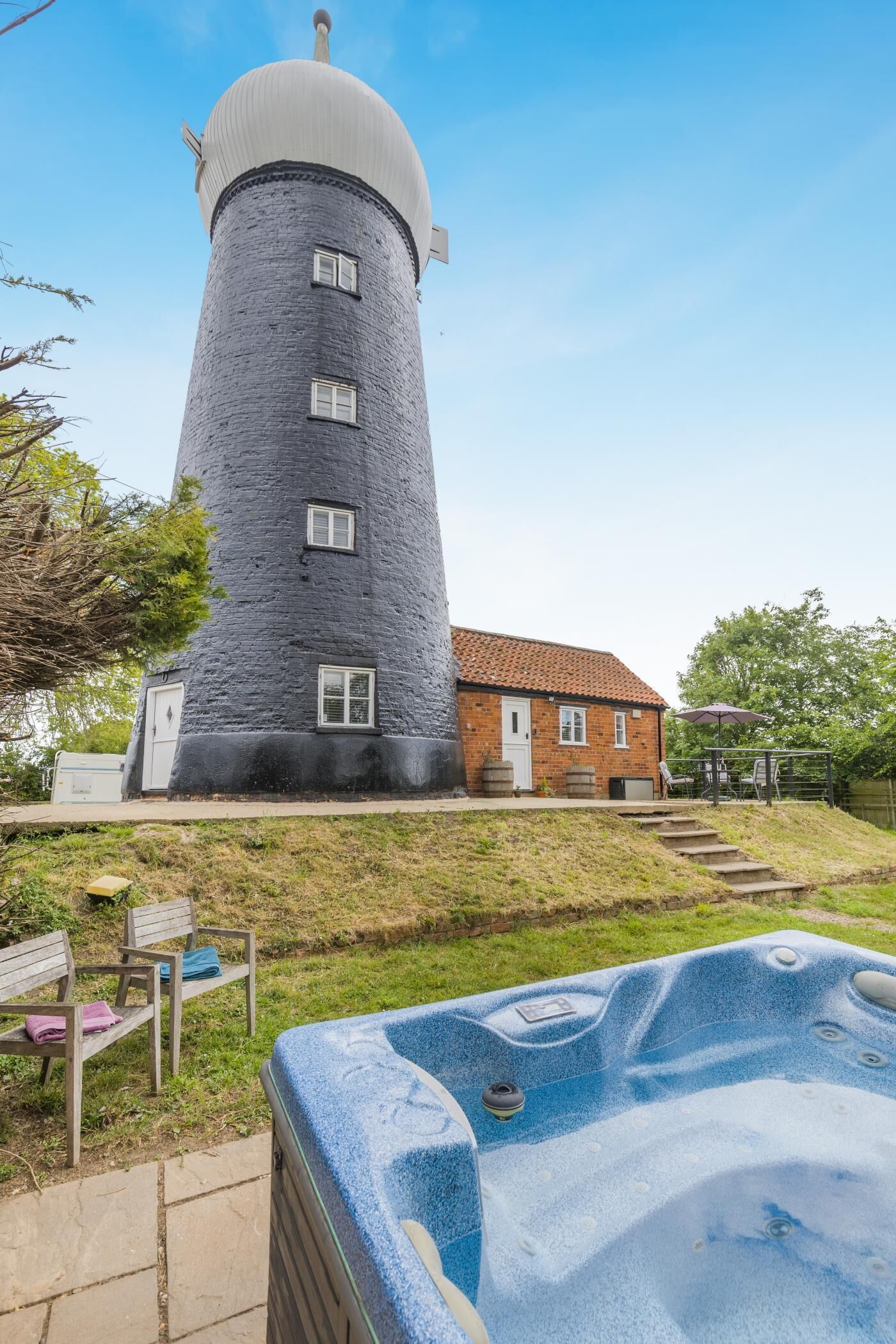 Een stenen toren met een huis van baksteen, een jacuzzi en een gazon met bankjes.