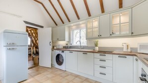 A modern kitchen with white cabinets, a built-in washing machine, and a large window. - 2 Bed in Wrangle (oc-t37494) (Old Leake)