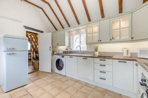 Eine moderne Küche mit weißen Schränken, einer integrierten Waschmaschine und einem großen Fenster.