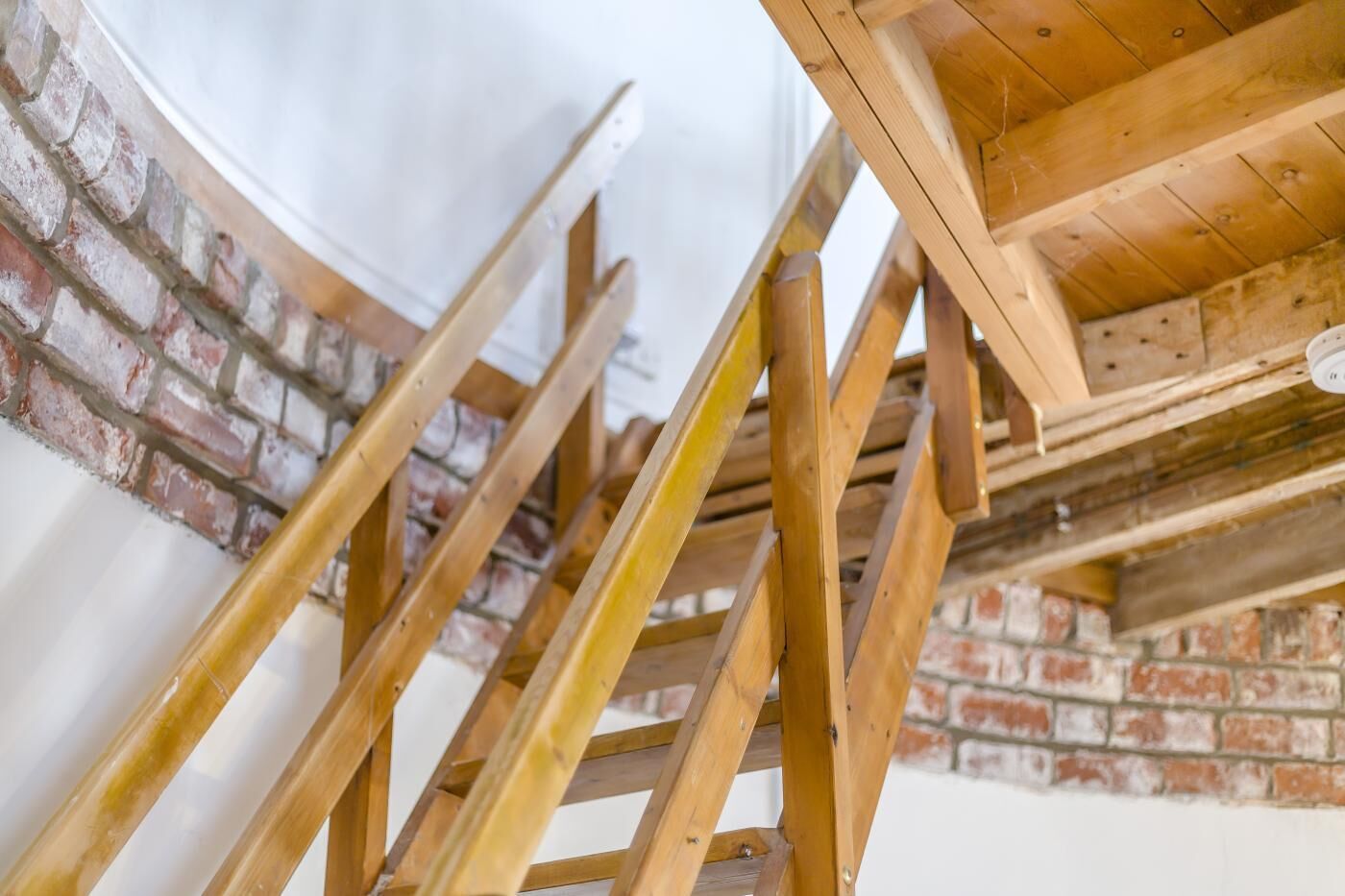 Eine Holztreppe vor einer Backsteinwand.