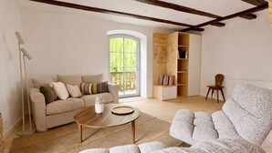 Un salon comprenant un canapé, un fauteuil, une table basse et une bibliothèque en bois.