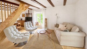 Un salon moderne avec un escalier, un canapé, deux fauteuils, une table basse et un téléviseur.