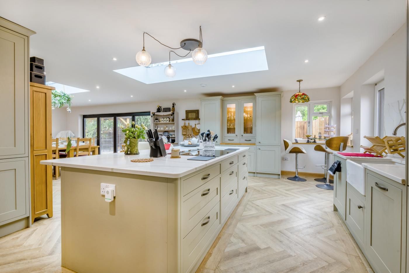 A spacious kitchen with a large island, modern pendant lighting, and a skylight.