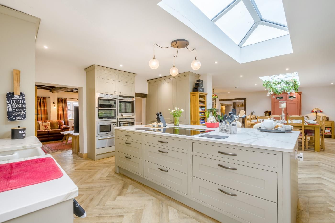 A modern kitchen with a central island, built-in ovens, and a skylight.