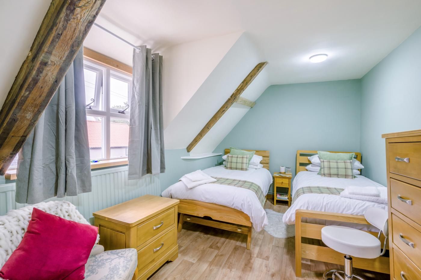 Ein Schlafzimmer mit zwei Betten, einer Holzkommode, einem kleinen Tisch und einer Bank.