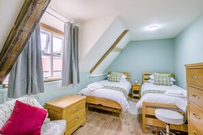 A bedroom with two beds, a wooden dresser, a small table, and a bench. - 4 Bed in Whissonsett (oc-l36622) (Whissonsett)