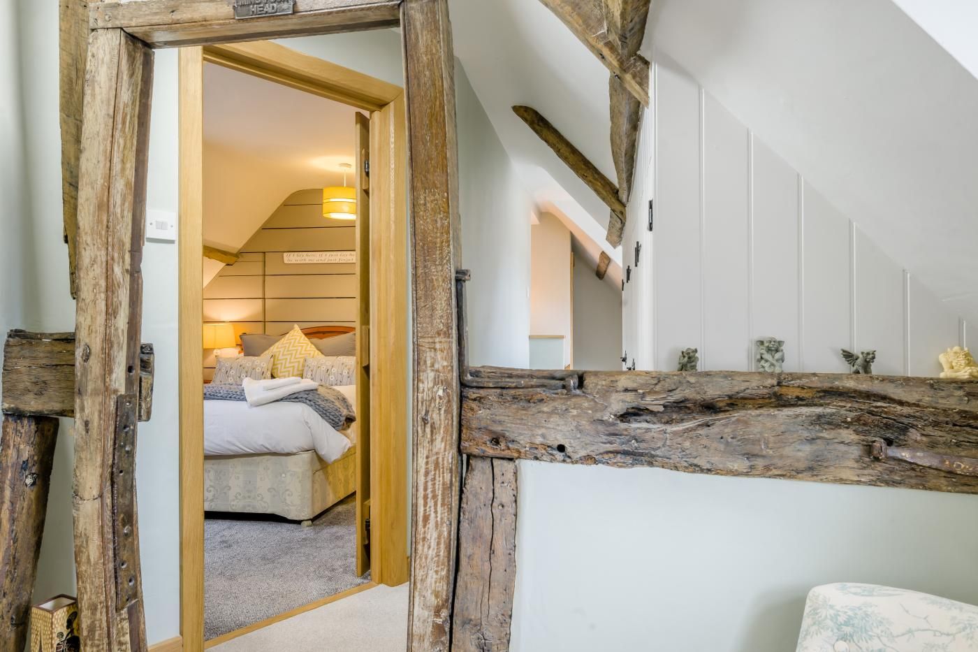 Un dormitorio con cama, cabecera de madera y vistas a una escalera.