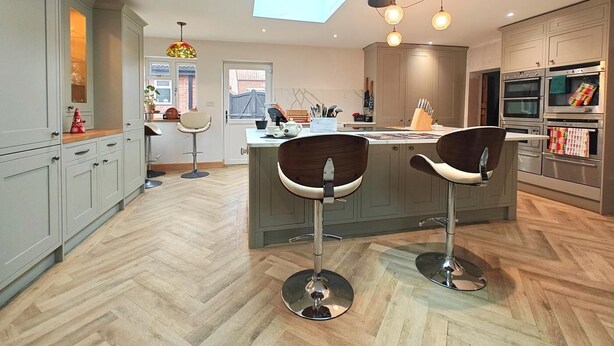 Een moderne keuken met een centraal kookeiland, barstoelen en geïntegreerde apparatuur.