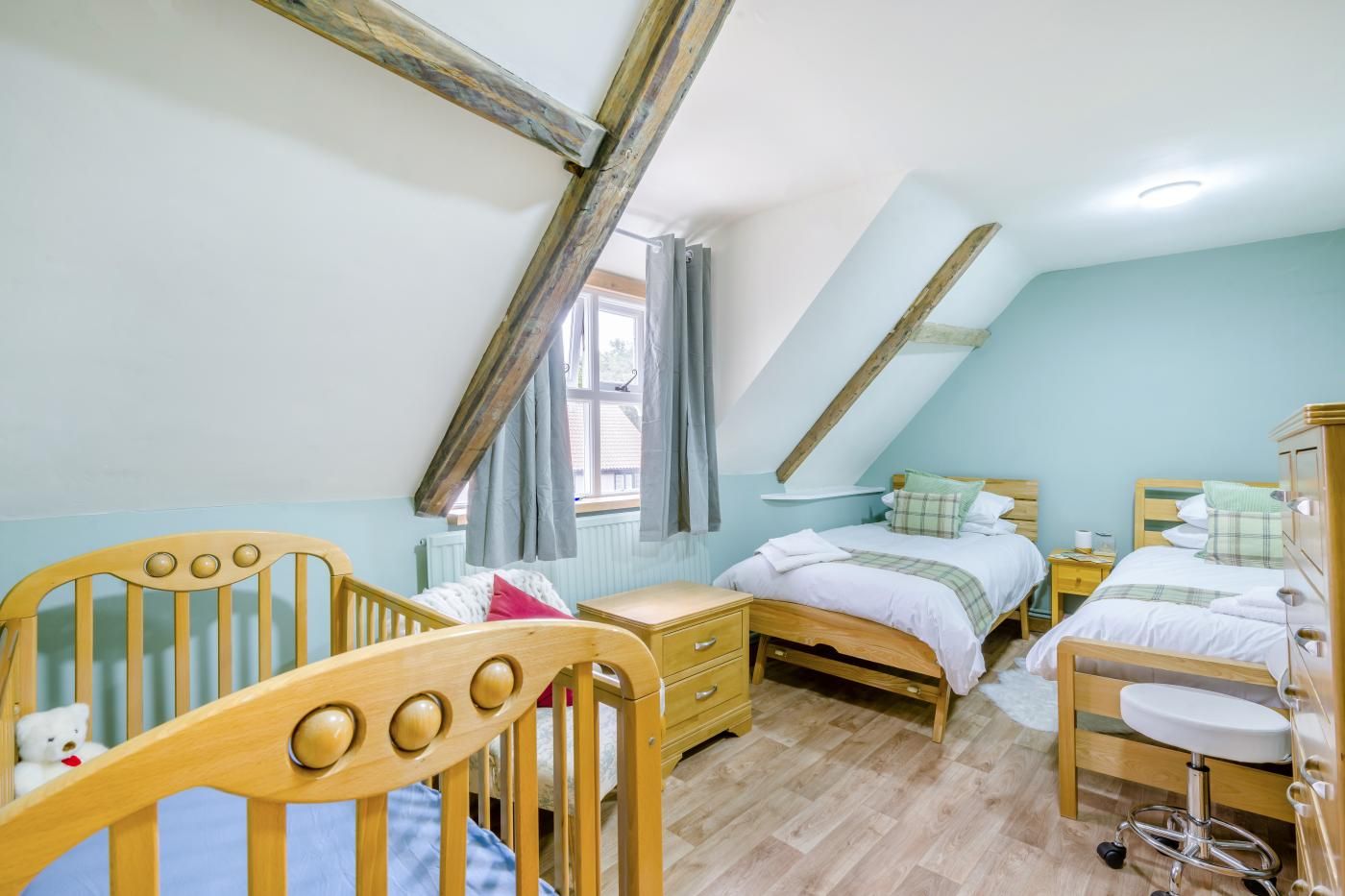 A bedroom with a sloped ceiling, wooden furniture, and a crib.