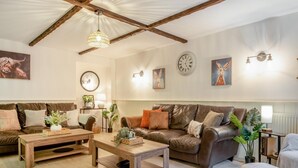 Un soggiorno con un divano in pelle marrone, un tavolino in legno e un lampadario.