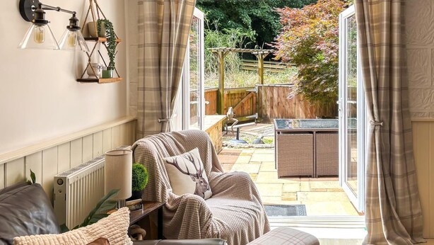Un accogliente soggiorno con divano, tavolino e vista su un giardino tramite una porta aperta.