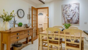 Zona pranzo con tavolo e sedie in legno, una sveglia, oggetti decorativi e un quadro raffigurante un leone.