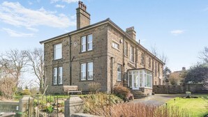 A two-story stone house with a conservatory, a garden with a pond, and a bench. - 2 Bed in Shepley (oc-c36884) (Shepley)