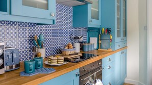 A kitchen with blue cabinets, a patterned backsplash, and various kitchen items on the counter.