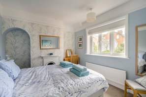 Ein Schlafzimmer mit Bett, Kamin, Fenster und Spiegel.