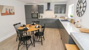 Una cocina moderna con armarios oscuros, una isla central y una zona de comedor con cuatro sillas.