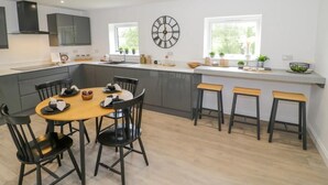 Una cocina moderna con una isla central, taburetes de bar y una mesa de comedor con sillas.