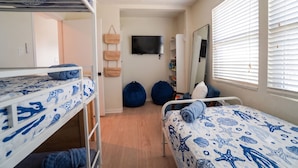 A bunk bed room with a TV, a mirror, and a window with blinds.