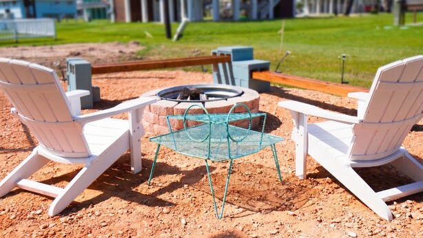 A patio with two Adirondack chairs, a metal table, and a fire pit.