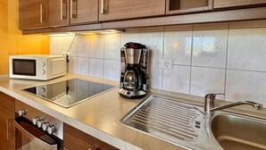 A kitchen with wooden cabinets, a microwave, a coffee maker, and a stainless steel sink. - Moderne Ferienwohnung mit Zwei Schlafzimmern (Sellin)