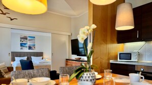 A hotel room with a dining area, a bed with a view, a TV, and a microwave. - Moderne Ferienwohnung mit Zwei Schlafzimmern (Sellin)