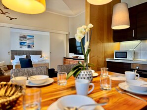 A hotel room with a dining area, a bed with a view, a TV, and a microwave. - Moderne Ferienwohnung mit Zwei Schlafzimmern (Sellin)