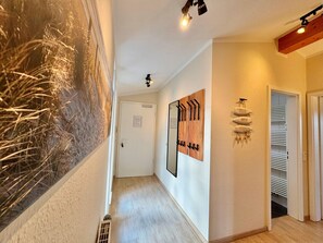 A hallway with a wooden floor, a white door, a wall-mounted coat rack, and a radiator. - Moderne Ferienwohnung mit Zwei Schlafzimmern (Sellin)