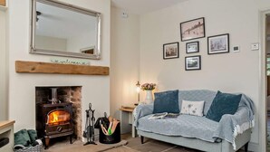 Ein gemütliches Wohnzimmer mit Kamin, einer Couch, einem Spiegel und gerahmten Bildern an der Wand.