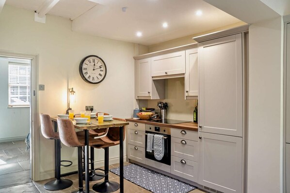 A kitchen with a dining table, chairs, a clock, cabinets, and a window. - 2 Bed in Cherry Burton (oc-c37535) (Cherry Burton)
