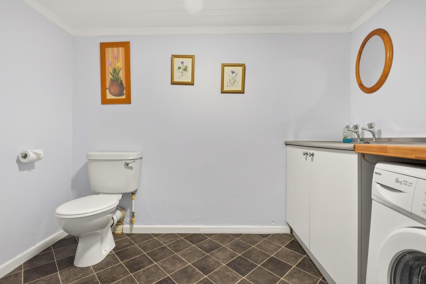 Ein Badezimmer mit Toilette, Waschmaschine und Spiegel.