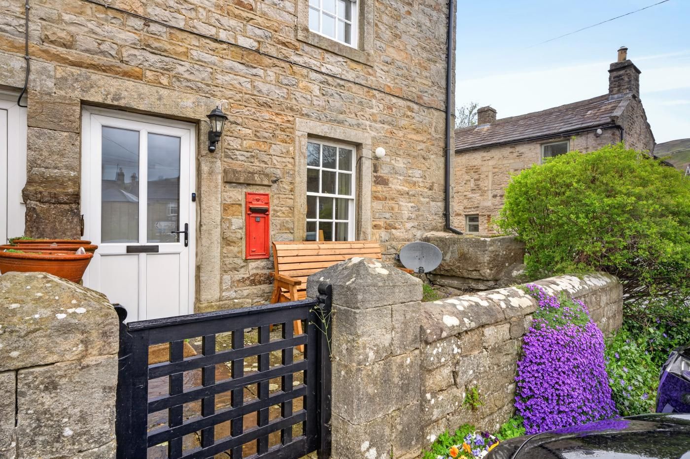 A stone building with a white door, a red mailbox, and a wooden bench outside.