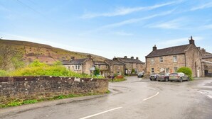 A rural street with stone houses, parked cars, and a hill in the background. - 2 Bed in Gunnerside (oc-g37866) (Gunnerside)
