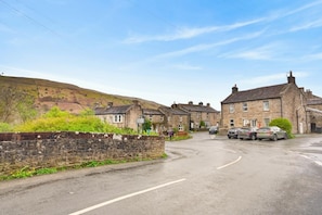 A rural street with stone houses, parked cars, and a hill in the background. - 2 Bed in Gunnerside (oc-g37866) (Gunnerside)