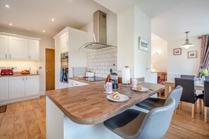 Eine moderne Küche mit weißen Schränken, einer Holz Arbeitsplatte und einem Essbereich mit Tisch und Stühlen.