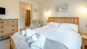 Una camera da letto con un letto, una sedia, una cassettiera e un quadro appeso al muro.