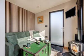 Una sala de estar moderna con un sofá, un aparador verde, una chimenea, un televisor y una puerta corrediza de vidrio.