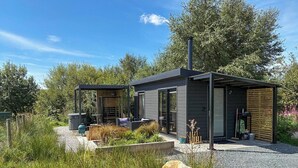 A modern house with a covered outdoor seating area, a chimney, and a garden with a gravel path. - 1 Bed in Austwick (oc-b37509) (Austwick)